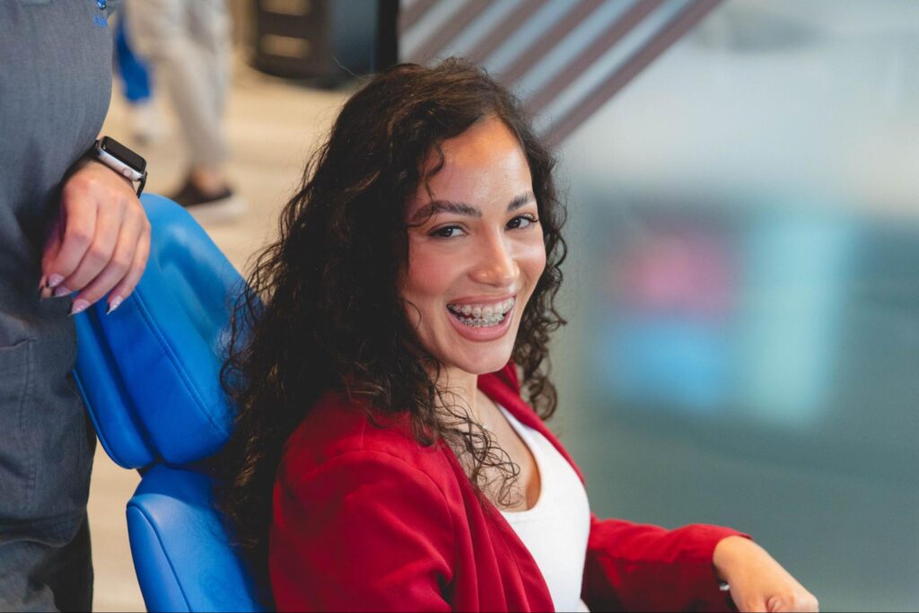 Smiling patient with braces sitting in orthodontic chair, showcasing personalized orthodontic care at Orthodontics of South Miami.