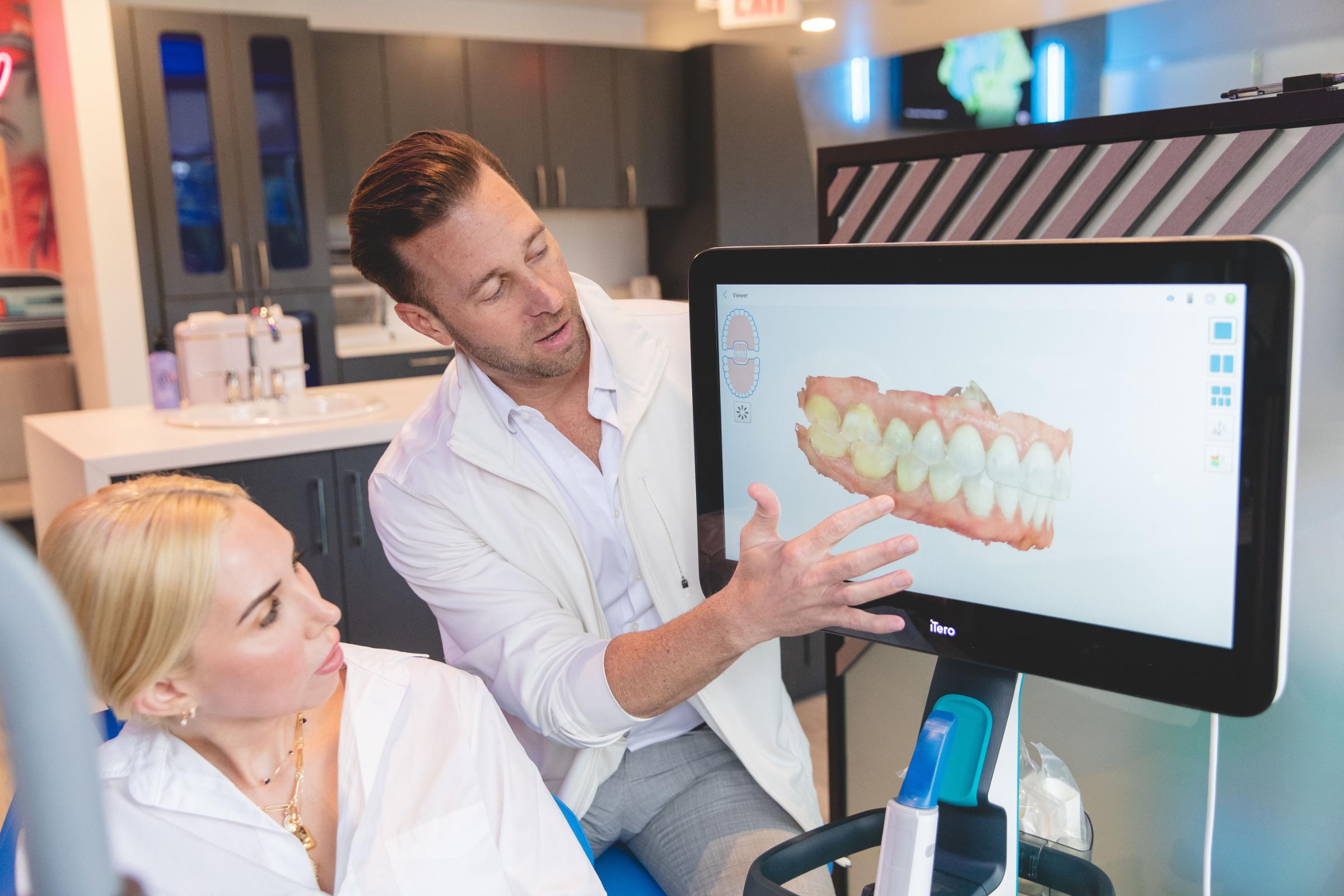 Orthodontist explaining treatment options using digital imaging to a patient in a modern orthodontic office.